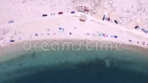 在雨伞和人的头顶上飞翔在克罗地亚帕格岛的偏僻海滩上视频的预览图