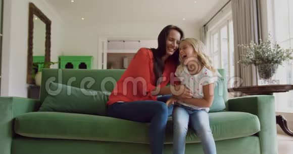 母亲和女儿一起在家里的沙发上玩耍视频的预览图