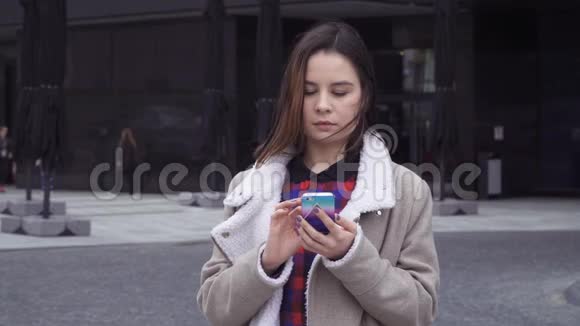 年轻的女人在玩智能手机视频的预览图