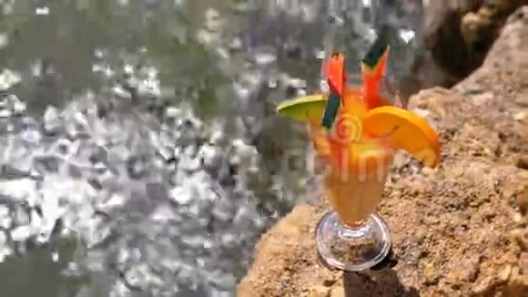 埃及海滩上一杯装有稻草的热带新鲜鸡尾酒矗立在红海背景的岩石上视频的预览图