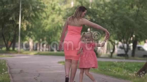 快乐的母亲和她的小女儿玩耍还有一个年轻的白种人妈妈穿着夏天的鲜艳衣服视频的预览图