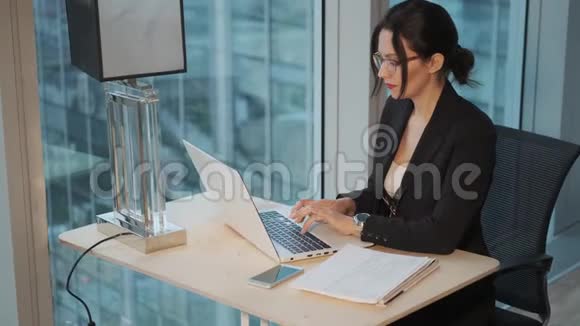 一位年轻妇女在现代办公室的电脑上工作的肖像视频的预览图