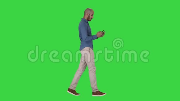 年轻人在绿色屏幕上行走和使用手机Chroma键视频的预览图
