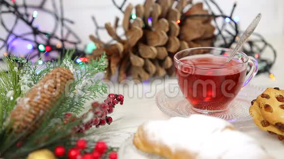 一杯带蜂蜜和牛角面包的茶雪中圣诞树的一根树枝圣诞灯视频的预览图