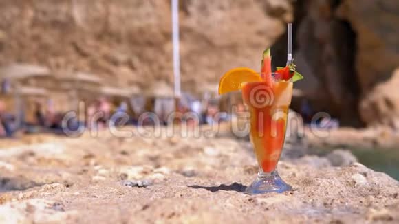 埃及海滩上的麦秆玻璃中的热带鲜榨果汁矗立在海边的岩石上视频的预览图