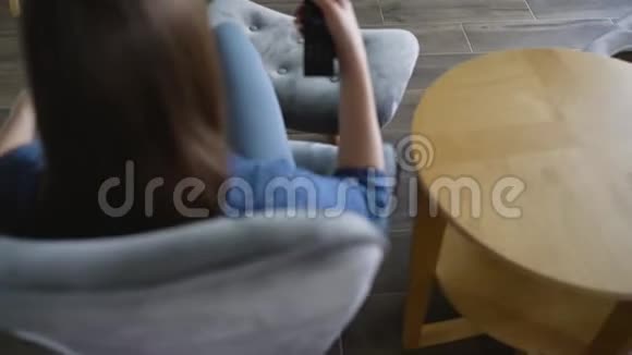女人坐在椅子上用绿色的屏幕看电视用遥控器切换频道铬键视频的预览图