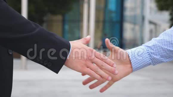 两个商人在城市环境中互相问候户外商务握手男性手臂在外面晃动视频的预览图