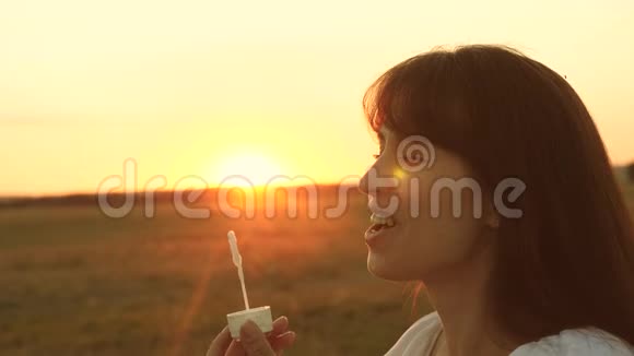 美丽的女人吹着透明的肥皂泡微笑着慢动作年轻女孩在公园玩耍吹吹风视频的预览图