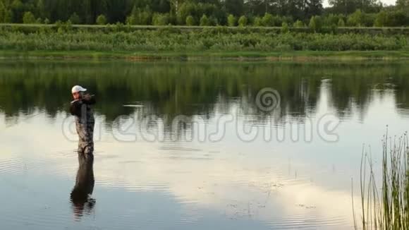 渔夫在一条平静的河里钓鱼穿着渔具的人在河里视频的预览图