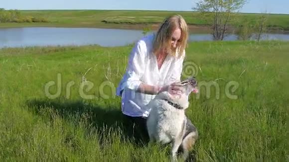 美丽的女孩在湖边草地上玩狗动物宠物朋友情感快乐微笑狗慢动作视频的预览图