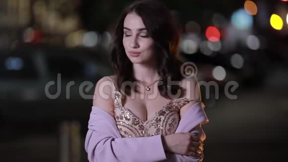 美丽迷人的女人在夜城看相机慢动作视频的预览图