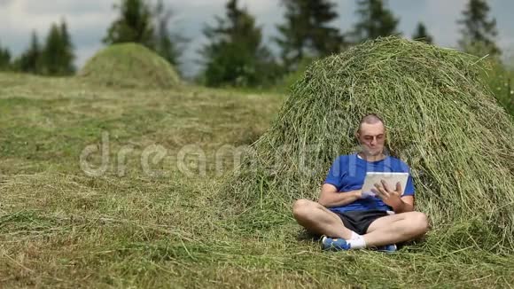 有平板电脑的人坐在干草堆附近视频的预览图