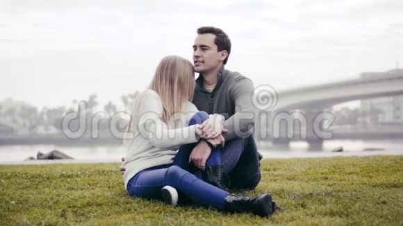 恋爱中的情侣坐在草地上拥抱在公园里视频的预览图