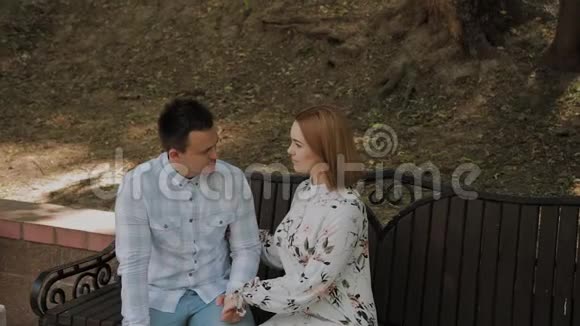美丽幸福的恋爱情侣坐在公园的长椅上聊天视频的预览图