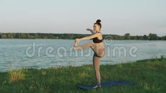 早上练习瑜伽的漂亮女人做瑜伽的女孩在草地上移动视频的预览图