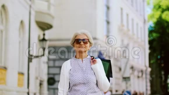 带着购物袋的老妇人在城里散步视频的预览图