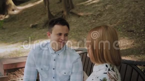 美丽幸福的恋爱情侣坐在公园的长椅上聊天视频的预览图