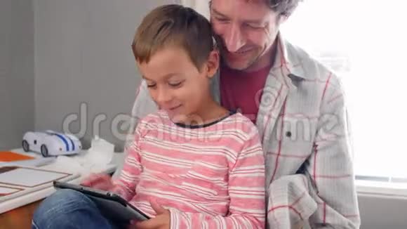 父亲和儿子使用数码平板电脑坐在卧室视频的预览图