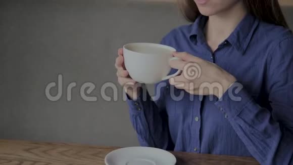 一个漂亮的女孩坐在咖啡馆里喝咖啡视频的预览图