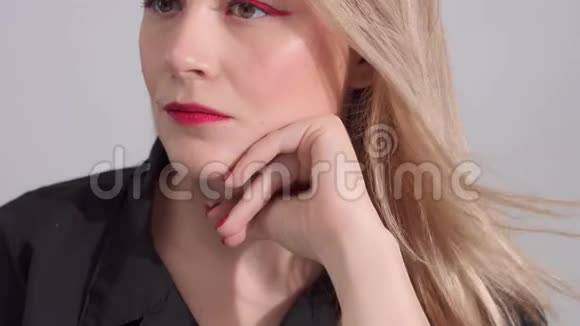 一位金发女人在工作室里化妆着鲜艳的红色视频的预览图