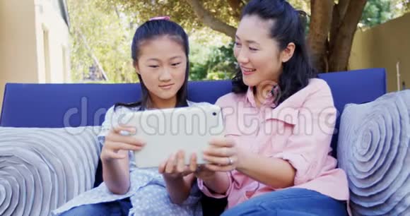 母亲和女儿在沙发上放松使用数字平板电脑4k视频的预览图