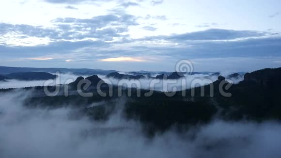 春天雾蒙蒙的早晨森林景观雄伟的山峰划破了灯光的薄雾深谷充满了五颜六色的雾和山丘视频的预览图