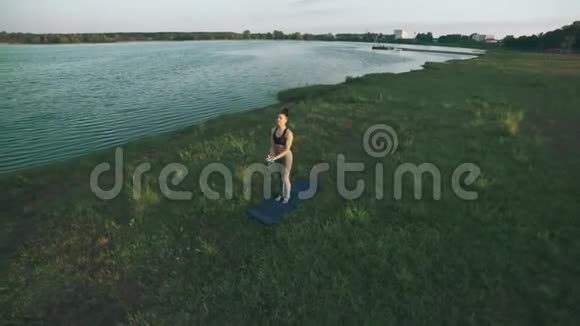 做瑜伽的年轻女孩在绿草上移动早上练习瑜伽的女人视频的预览图