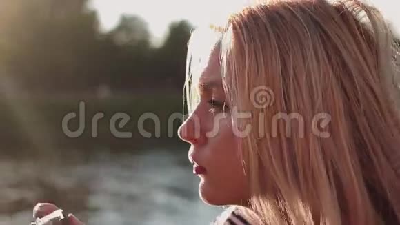年轻女子带着摄像机拍摄河流的照片视频的预览图