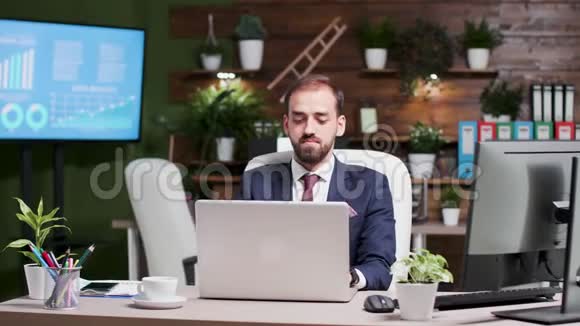 年轻英俊的商人在笔记本电脑上工作的肖像视频的预览图