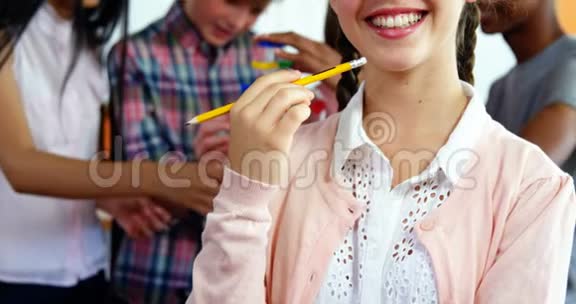 微笑的女学生在教室里拿铅笔的画像视频的预览图