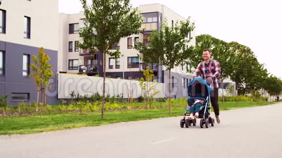 父亲带着婴儿在婴儿车里沿着城市散步视频的预览图