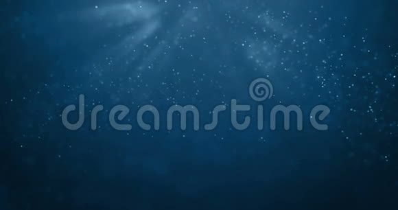 来自水下背景的深蓝色海浪的无缝环路粒子流动光线闪耀视频的预览图