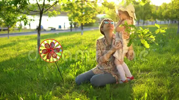 母亲和女儿在日落时快乐地一起在草地上玩耍视频的预览图
