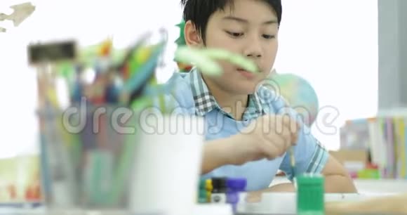 快乐的亚洲可爱的孩子用笑脸在纸上画水色视频的预览图