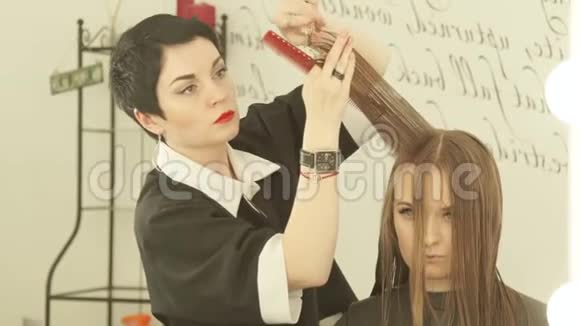 女发型师在美发沙龙用剪刀剪长发为女性剪发剪短视频的预览图