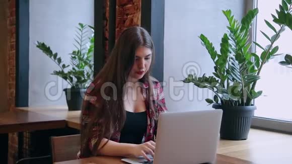 一位漂亮的女商人正坐在一张桌子旁在咖啡馆里拿着笔记本电脑工作视频的预览图