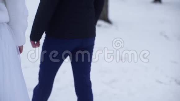 年轻的新婚夫妇走在外面在冬天或夏天新娘和新郎一起在公园里散步牵着手视频的预览图