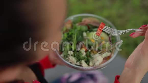 坐在草地上吃沙拉的女人视频的预览图
