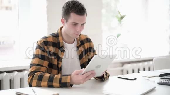 休闲青年男子在平板电脑上上网视频的预览图