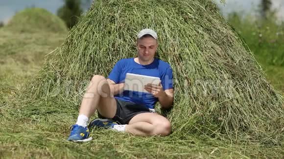 有平板电脑的人坐在干草堆附近视频的预览图