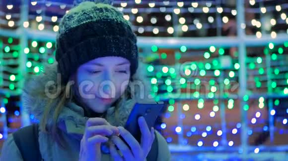 年轻漂亮的女人晚上在城里用智能手机视频的预览图