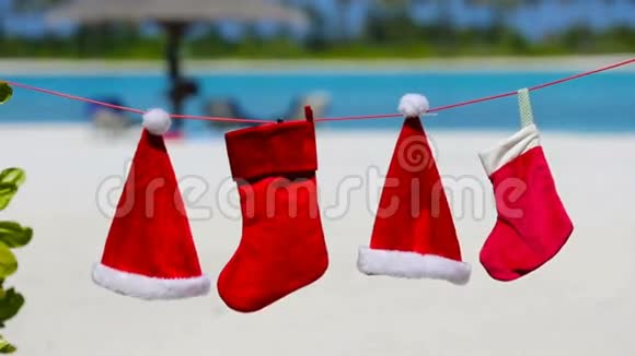 热带海滩上挂着红色圣诞帽和圣诞袜视频的预览图