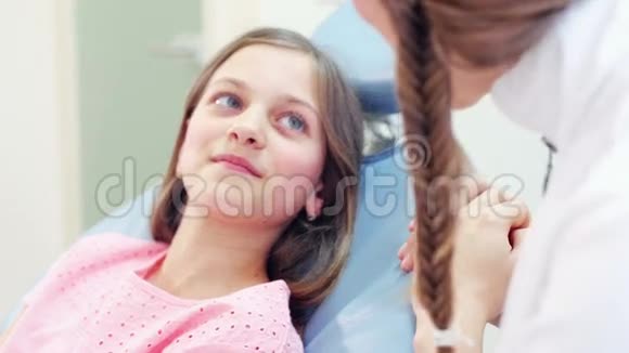 把坐在牙科椅上和牙医说话的小女孩关起来视频的预览图