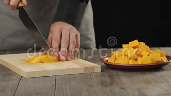 奶油南瓜汤烹饪健康食品厨师在木桌上把鲜橙南瓜切成小块侧视4K视频的预览图