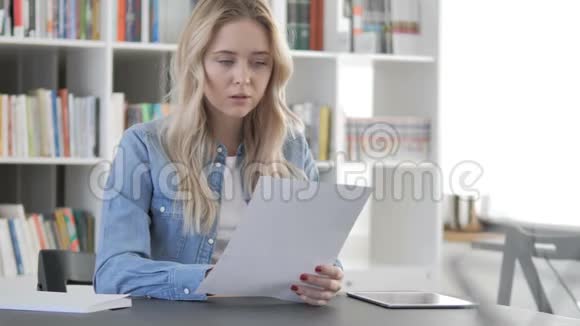 青年妇女阅读合同办公室文件视频的预览图