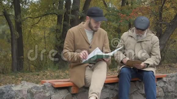 孙子和爷爷在公园的长凳上视频的预览图