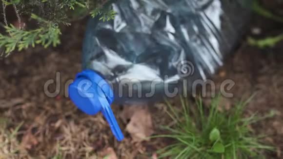 蓝色的大塑料瓶躺在公园森林里的树上扔出不回收的垃圾和污染视频的预览图