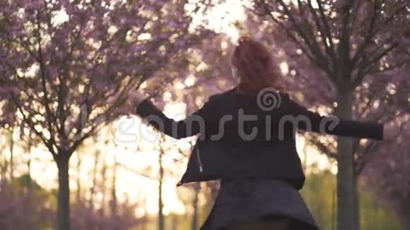 快乐的年轻旅游舞蹈家女人在樱花樱花公园享受自由时光白种人红发女孩视频的预览图
