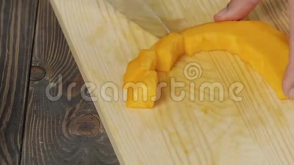 奶油南瓜汤烹饪健康食品厨师在木桌上把鲜橙南瓜切成小块侧视视频的预览图