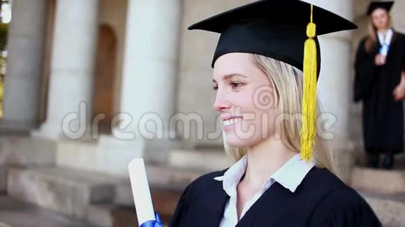 微笑的金发学生拿着她的文凭视频的预览图